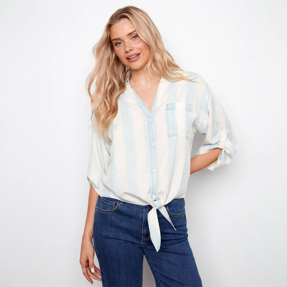 Woman wearing a light blue and white striped shirt with rolled-up sleeves and blue jeans on a white background