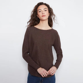A woman modeling a dark brown knit sweater with a wide boat neckline and long sleeves, paired with blue jeans, against a plain light gray background.