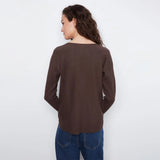 A woman shown from the back wearing a dark brown long-sleeve knit top and blue jeans against a plain white background.