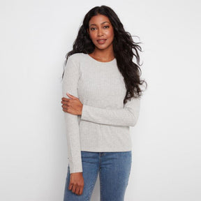 A woman modeling a light gray ribbed knit long-sleeve top with blue jeans, standing against a plain white studio background.