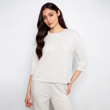 Woman wearing a light gray sweater and pants against a white background