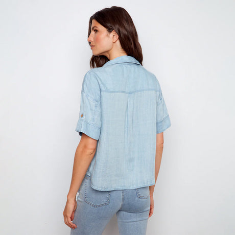 Woman wearing a light blue denim shirt and jeans on a white background