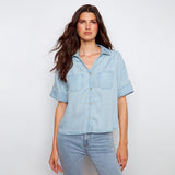 Woman wearing a light blue denim shirt and jeans on a white background