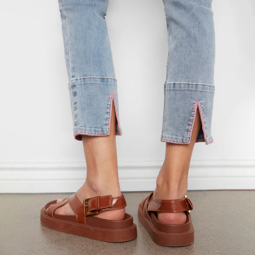 Brown platform sandals worn with light blue jeans on a neutral background