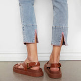 Brown platform sandals worn with light blue jeans on a neutral background