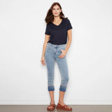 Woman wearing a navy t-shirt and light blue jeans against a white background