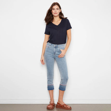 Woman wearing a navy t-shirt and light blue jeans against a white background