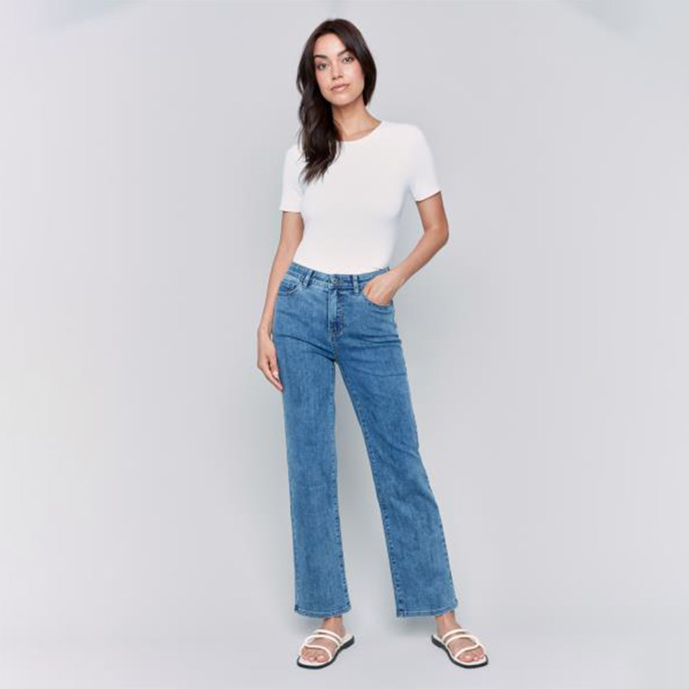 Woman wearing a white top and blue jeans on a gray background