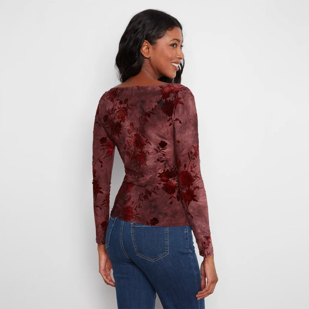 A woman wearing a long-sleeve dusty rose top with a dark red floral pattern, shown from the back against a plain white background.