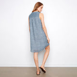 Woman wearing a blue patterned dress against a white wall