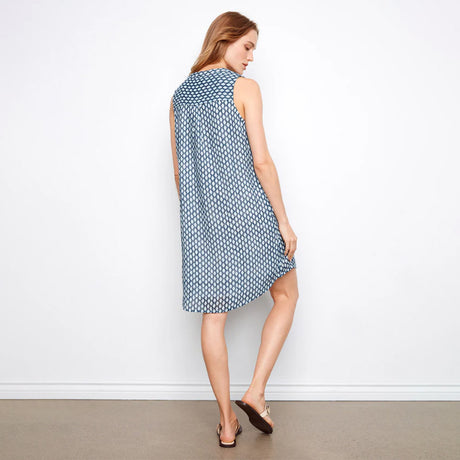 Woman wearing a blue patterned dress against a white wall