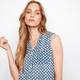 Woman wearing a blue patterned sleeveless top against a white background