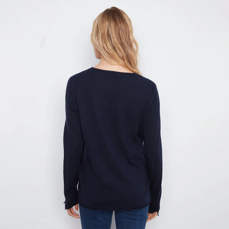 A woman viewed from behind wearing a dark navy long-sleeve knit top and blue jeans against a plain white background.