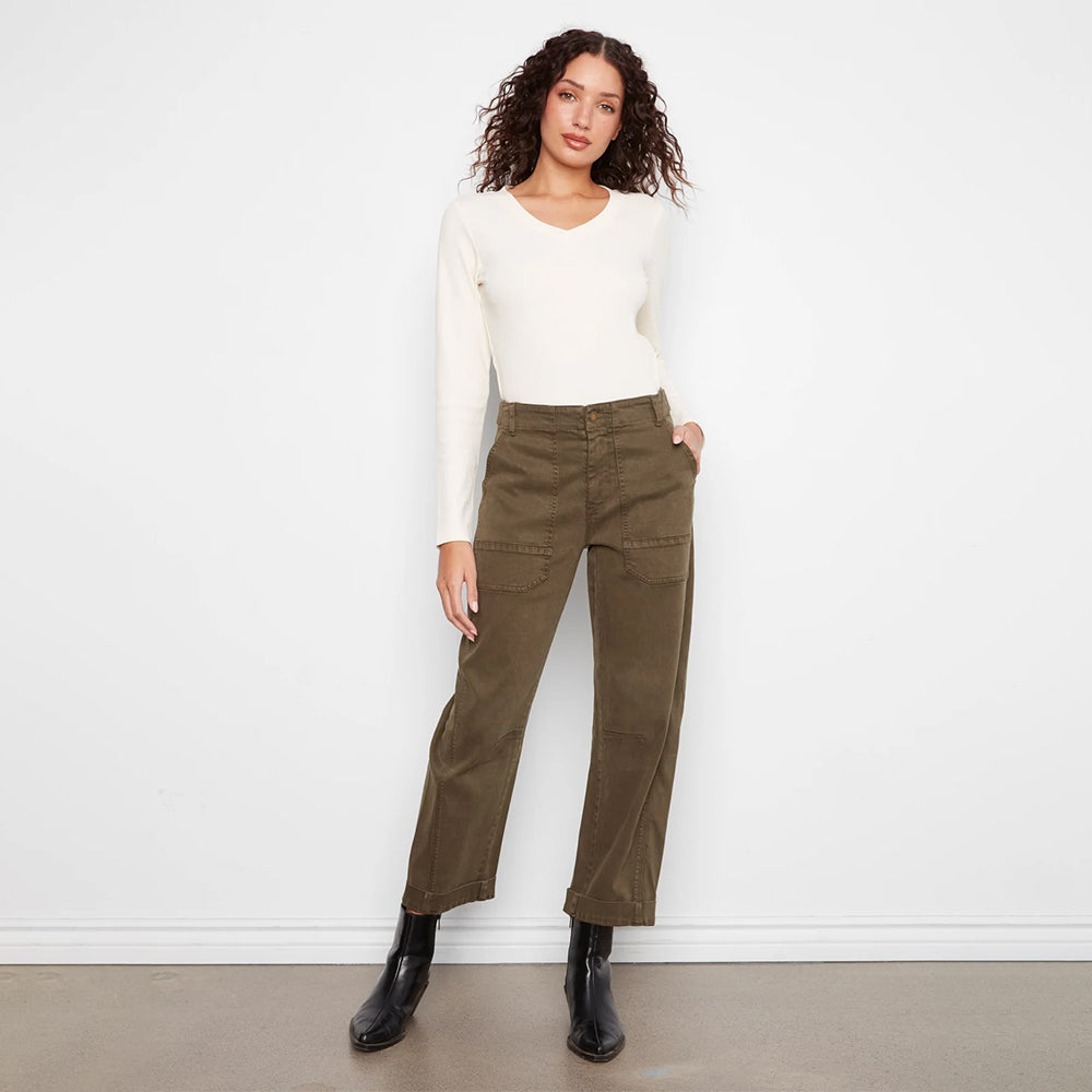 A model wearing olive green wide-leg cropped pants, a cream long-sleeve top, and black ankle boots, standing against a plain white wall.