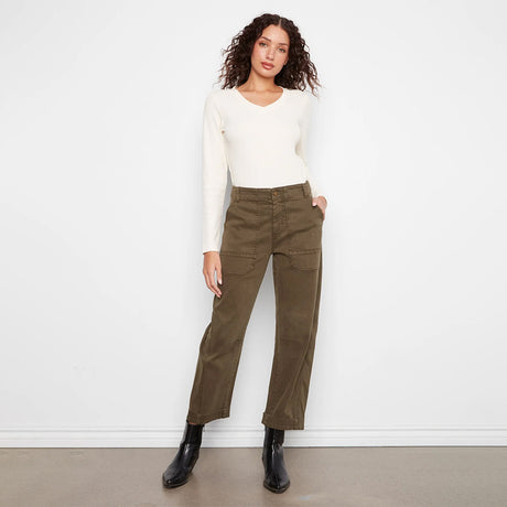 A model wearing olive green wide-leg cropped pants, a cream long-sleeve top, and black ankle boots, standing against a plain white wall.