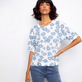 Woman wearing a white blouse with blue floral pattern and blue jeans on a white background