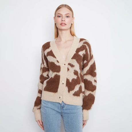 A woman modeling a fuzzy knit cardigan with a brown and beige abstract pattern, paired with light blue jeans, against a plain white studio background.