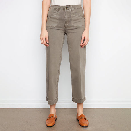 Person wearing beige pants and brown shoes on a plain background