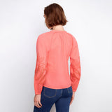 Person wearing a coral long-sleeve top with lace details on a white background
