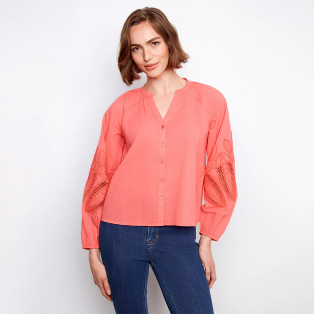 Woman wearing a coral blouse and blue jeans on a white background