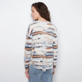 A woman shown from the back wearing a fuzzy knit sweater with horizontal watercolor-style stripes in cream, brown, blue, and gray, paired with light blue jeans against a plain white background.