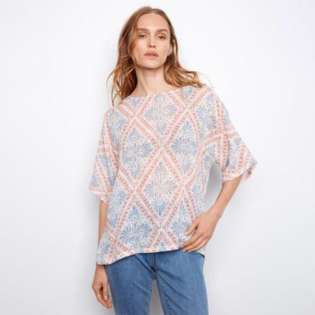 Woman wearing a patterned blouse and jeans on a white background