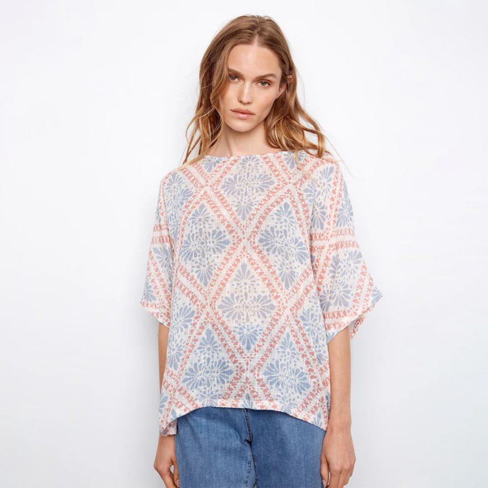 Woman wearing a patterned top with a plain background