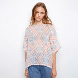 Woman wearing a patterned top with a plain background