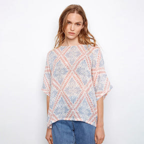 Woman wearing a patterned top with a plain background