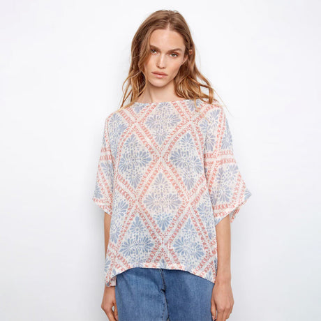 Woman wearing a patterned top with a plain background