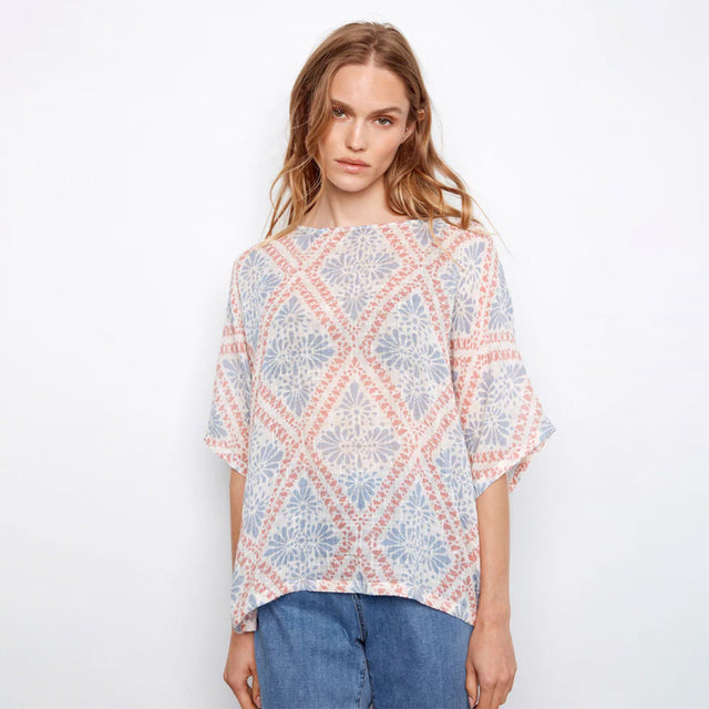 Woman wearing a patterned top with a plain background