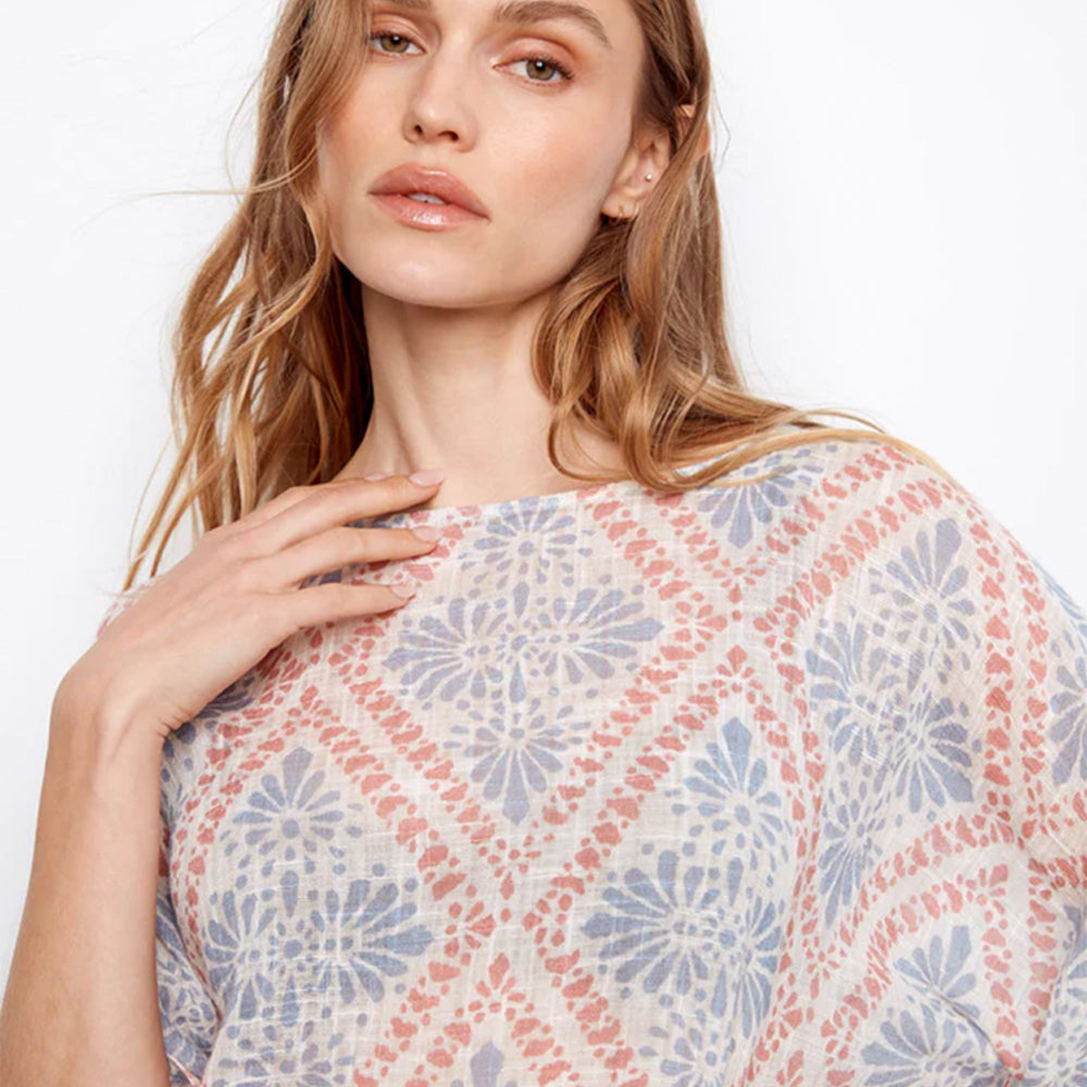 Woman wearing a patterned top with a plain background