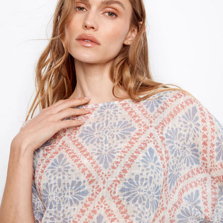 Woman wearing a patterned top with a plain background
