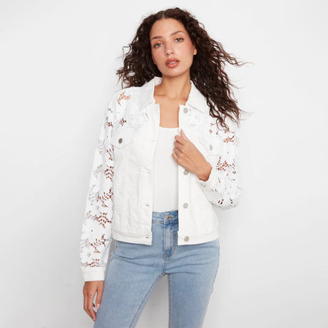 Woman wearing a white floral embroidered jacket and blue jeans on a light gray background