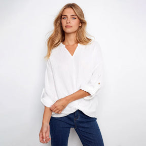 Woman wearing a white blouse and blue jeans against a plain background