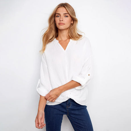 Woman wearing a white blouse and blue jeans against a plain background
