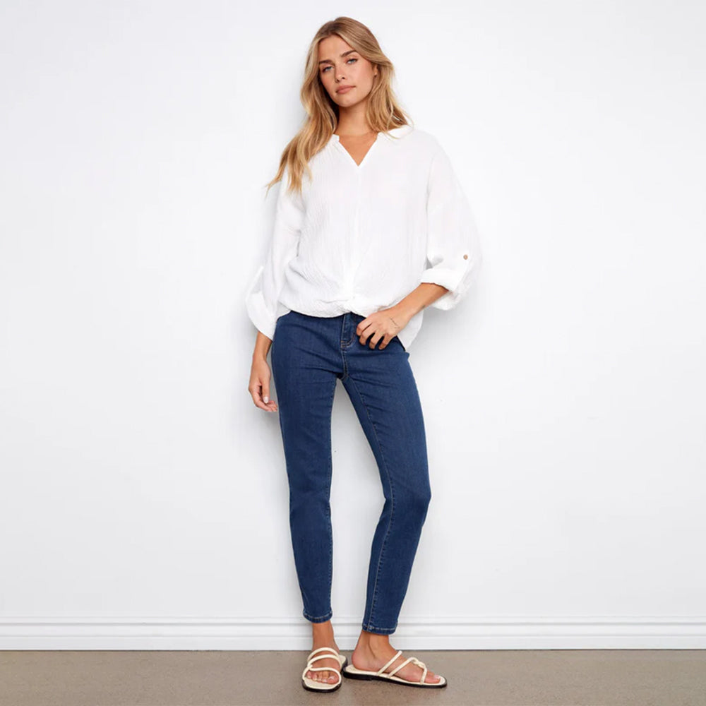 Woman wearing a white blouse and blue jeans against a white background