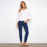 Woman wearing a white blouse and blue jeans against a white background