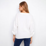 Woman wearing a white blouse and blue jeans on a plain background