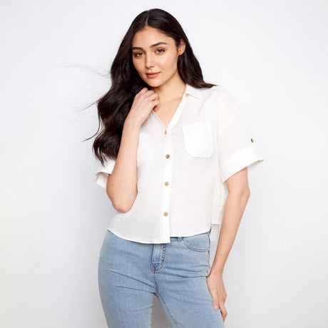 Woman wearing a white blouse and light blue jeans against a plain background