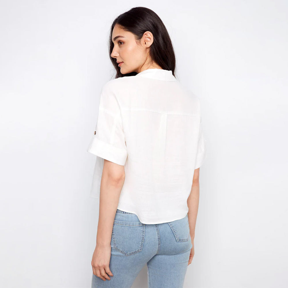 Woman wearing a white blouse and light blue jeans against a plain background