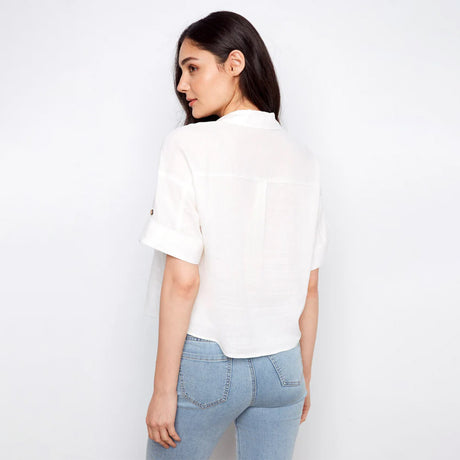 Woman wearing a white blouse and light blue jeans against a plain background
