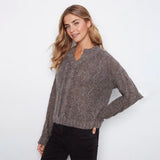 A woman modeling a brown and gray textured knit sweater with a scalloped V-neckline, paired with black pants, against a plain white studio background.