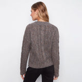 A woman viewed from the back wearing a textured, cable-knit crewneck sweater in a heathered brown and gray color, paired with black pants, against a plain white background.