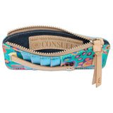 A small zip pouch with a colorful abstract pattern in blue, pink, orange, and green, featuring tan leather trim, a zipper pull, and an interior label that reads 'CONSUE'.