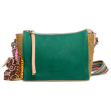 Green leather crossbody bag with cork accents and decorative charm on a white background