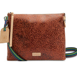 Brown leather crossbody bag with intricate pattern and colorful strap on a white background