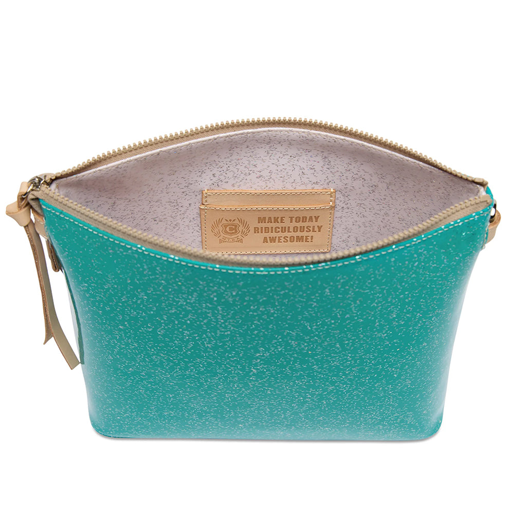 A turquoise glitter cosmetic pouch with a gold zipper and a tan leather brand patch inside, shown open on a white background.