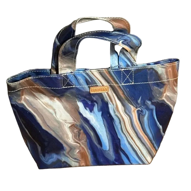 Blue and silver marbled handbag on a wooden surface with a neutral background