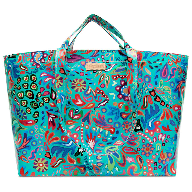 A large tote bag with a vibrant, multicolored psychedelic paisley pattern on a turquoise background, featuring dual top handles and a small metallic brand plaque.